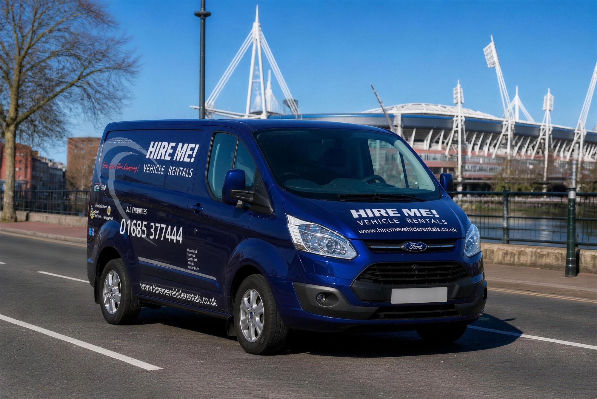 A Hire Me! Vehicle Rentals van in Cardiff, with the Principality Stadium behind it.