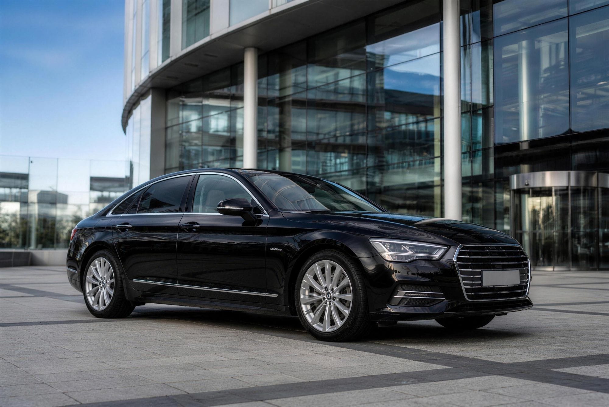 Chauffeur-driven saloon waiting outside an office building, representing the corporate chauffeur service for Cardiff business clients.